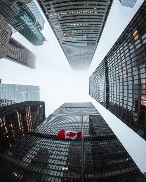 Free Looking up at Toronto skyscrapers with a Canadian flag on a cloudy day. Stock Photo