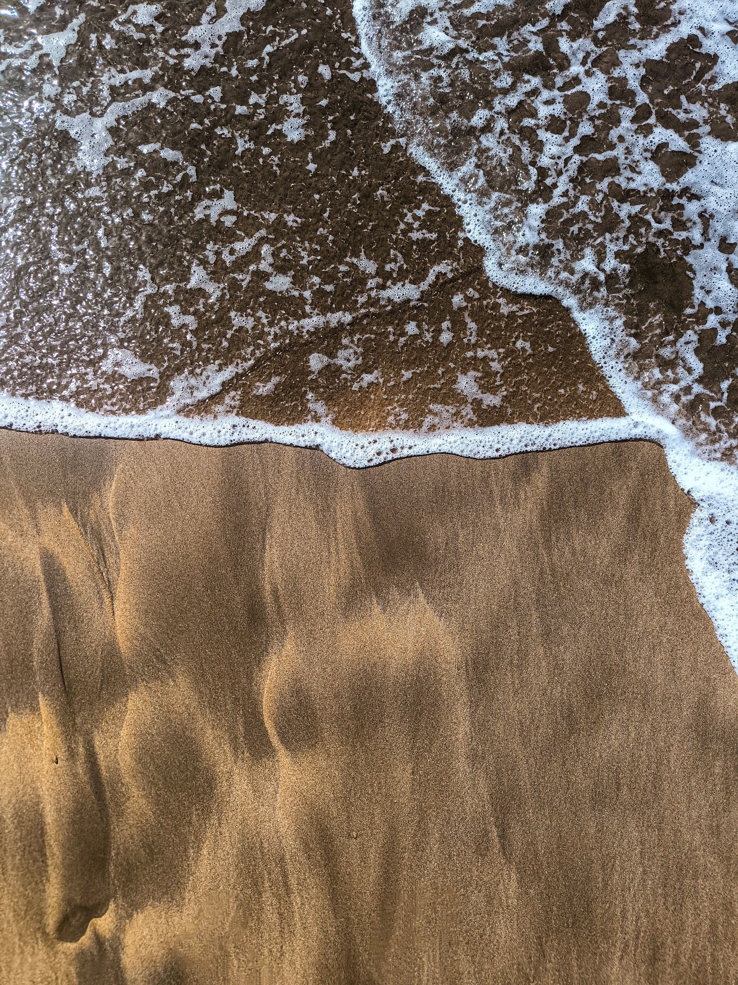 Serene Beach Wave and Sand Texture Close-Up · Free Stock Photo