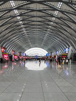 Spacious and bustling interior of an airport terminal with unique architecture and travelers.