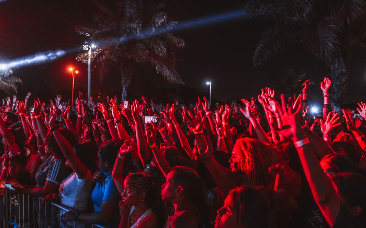 A lively crowd enjoying a night outdoor music festival under bright stage lights.