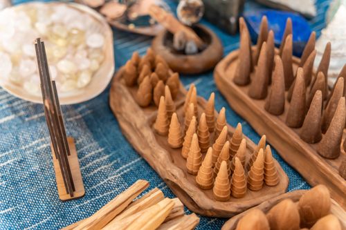 Free Incense cones and sticks artistically arranged on a wooden platter over blue fabric creating a tranquil ambiance. Stock Photo