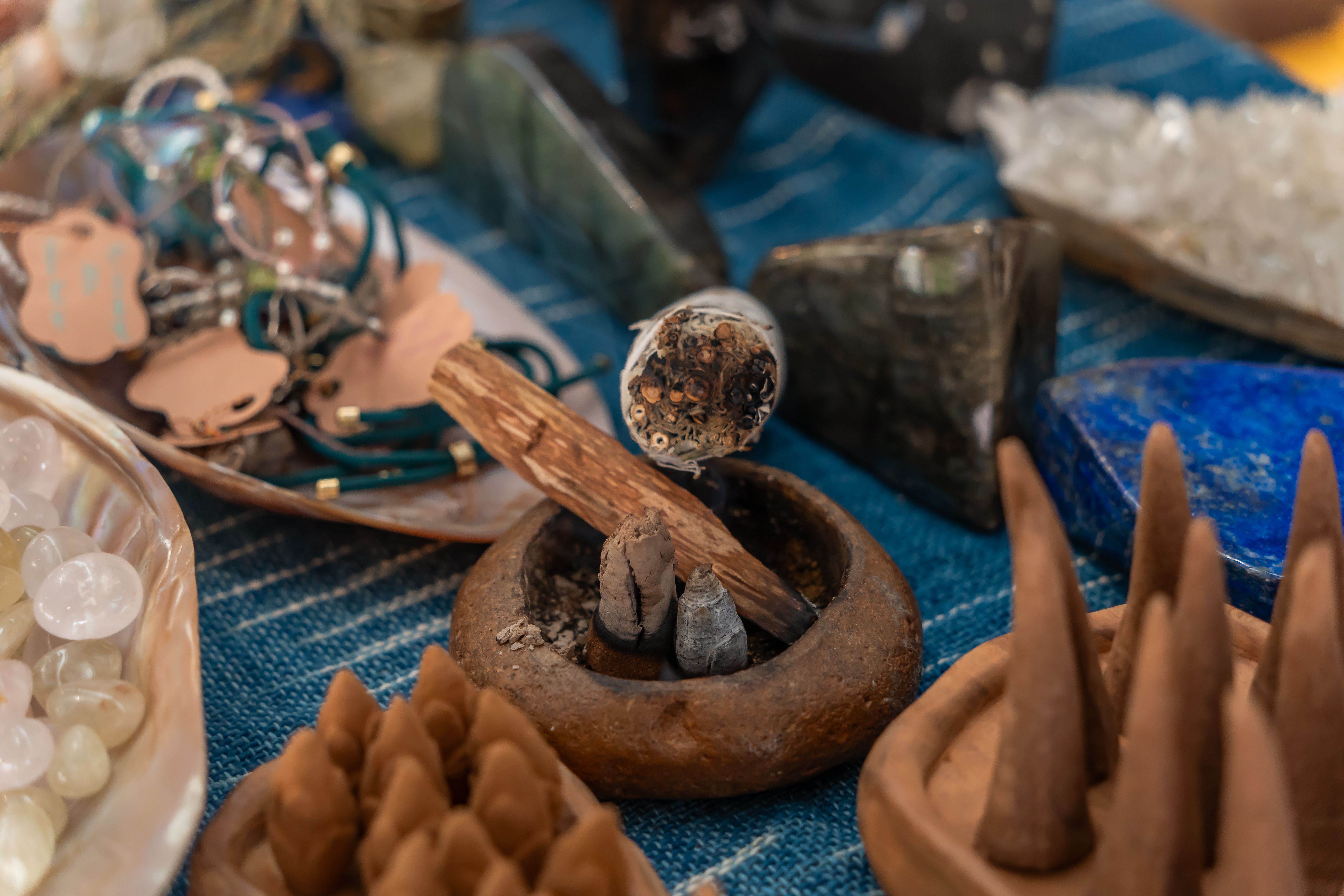 A vibrant collection of incense, crystals, and spiritual items on a textured blue fabric.