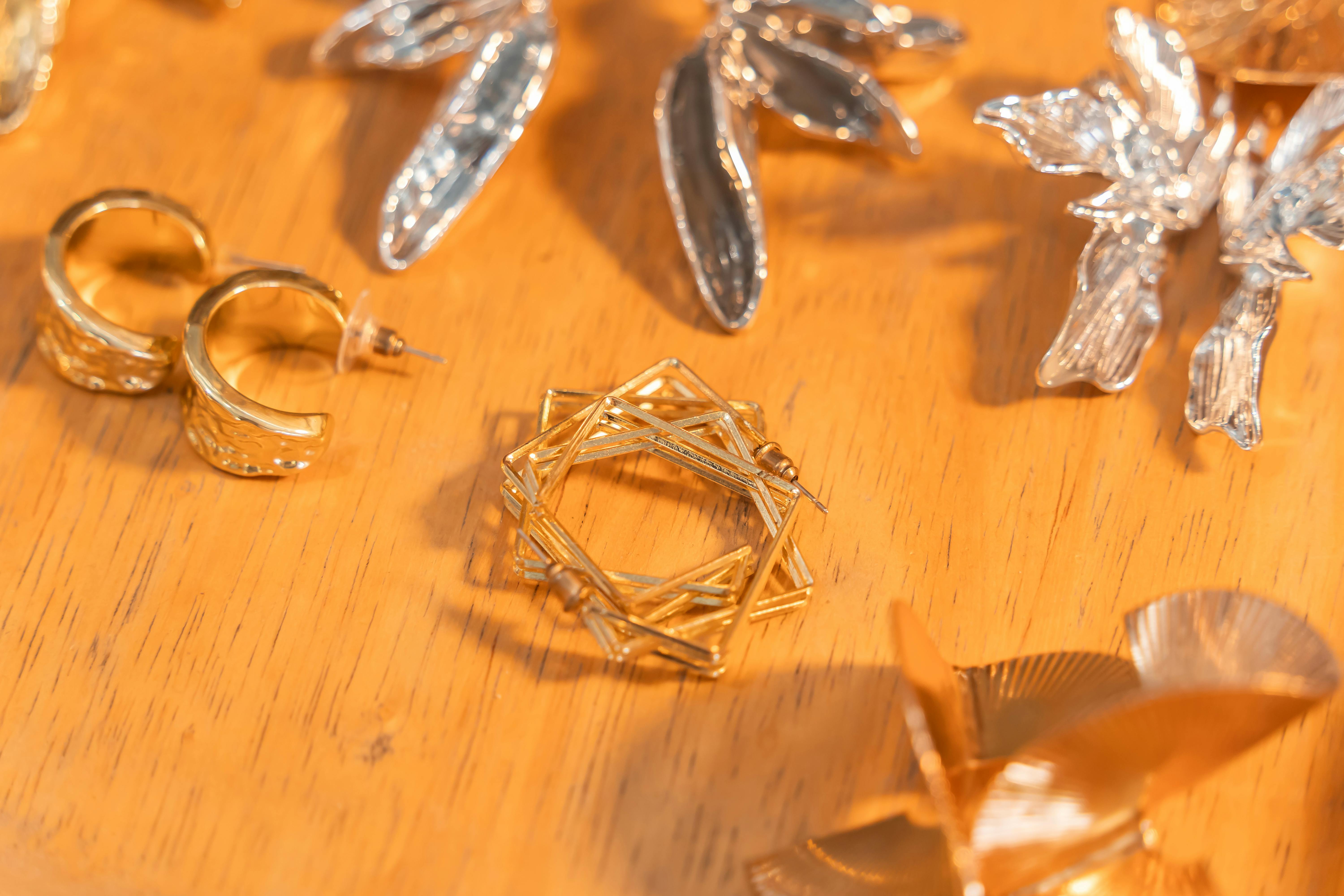 Close-up of elegant gold and silver earrings on a wooden surface, showcasing craftsmanship.