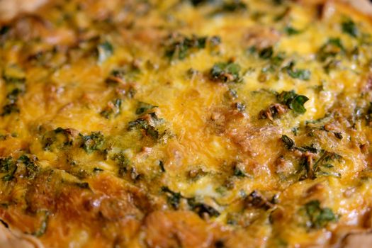 Close-up of a golden, cheesy quiche with kale, perfect for breakfast or brunch.