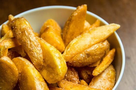 Close-up of golden crispy potato wedges in a bowl, perfect for food photography.