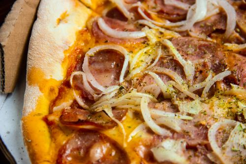 Free Mouth-watering close-up of pepperoni pizza with onions and herbs. Stock Photo