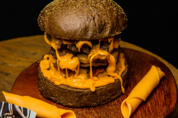Cheeseburger with melted cheese on a wooden board. Photo by Horizon Content on Pexels.