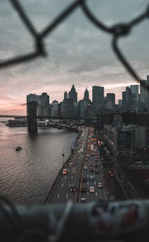 日落时分，铁丝网围栏后是纽约天际线与交通的迷人景色