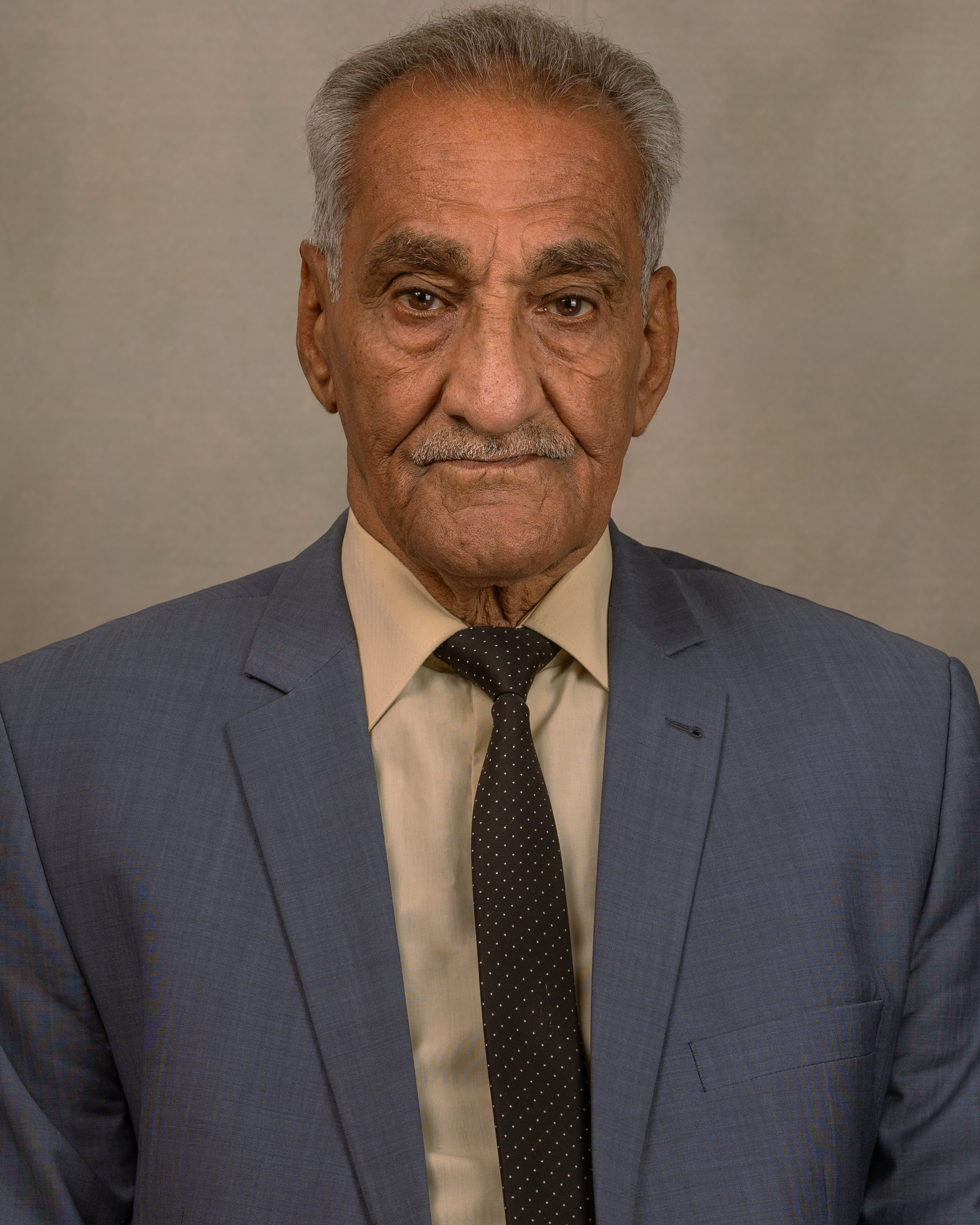 Senior adult man in a formal suit against a neutral background.