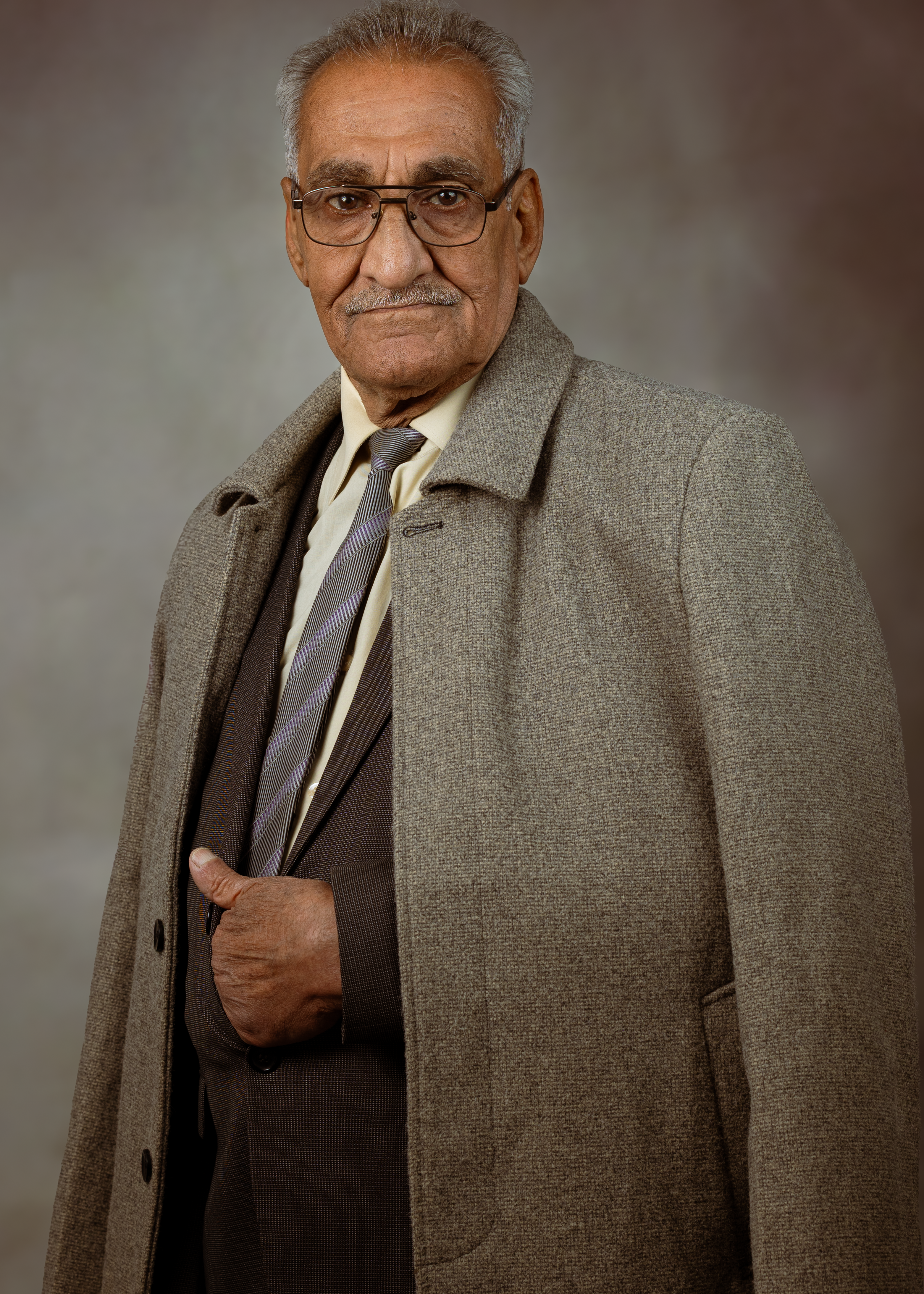 Portrait of a senior adult man in a gray coat and tie, exuding elegance.