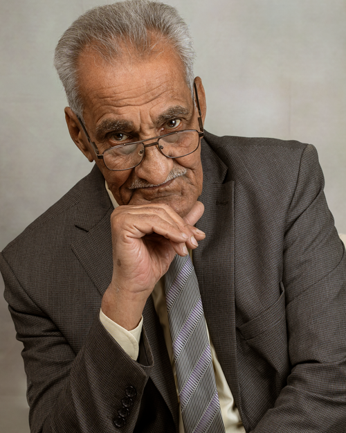 Free Elderly man in a suit with glasses, posing thoughtfully against a neutral background. Stock Photo