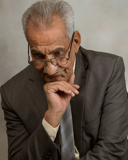 Free Elderly man in suit, deep in thought, with glasses and folded hands. Stock Photo