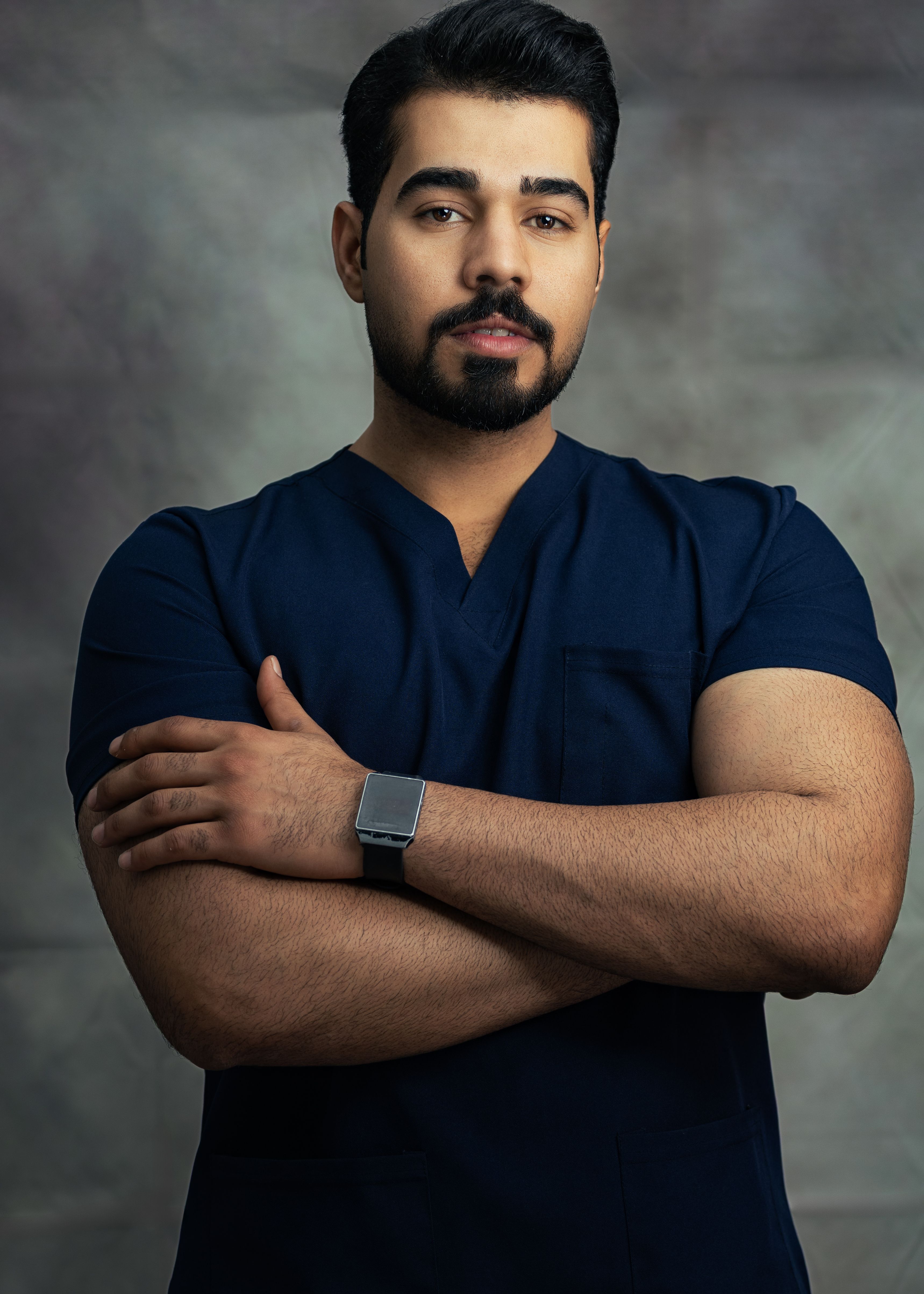 Portrait of a confident male professional in medical scrubs, arms crossed.