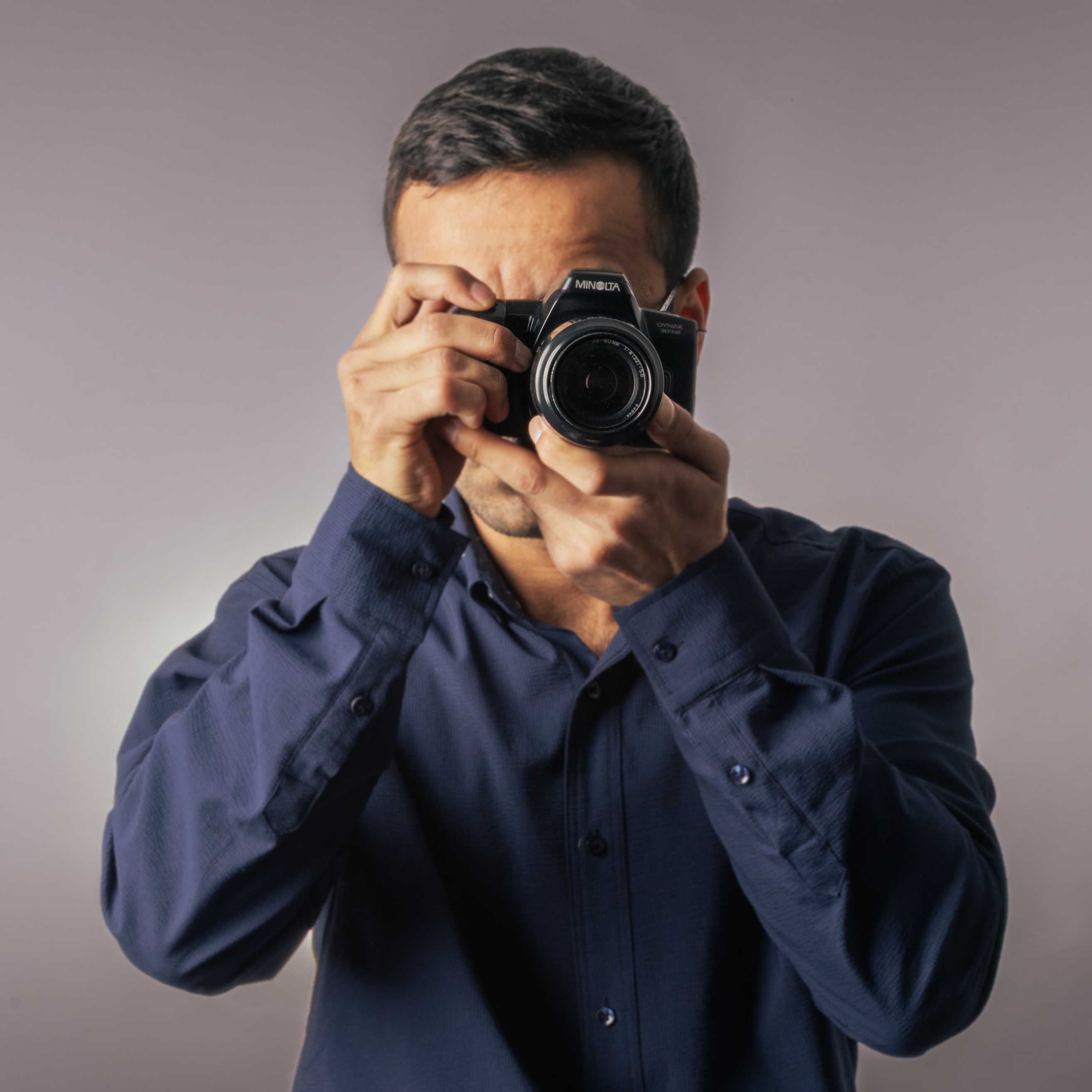 Man in blue shirt holding a camera taking a photo.