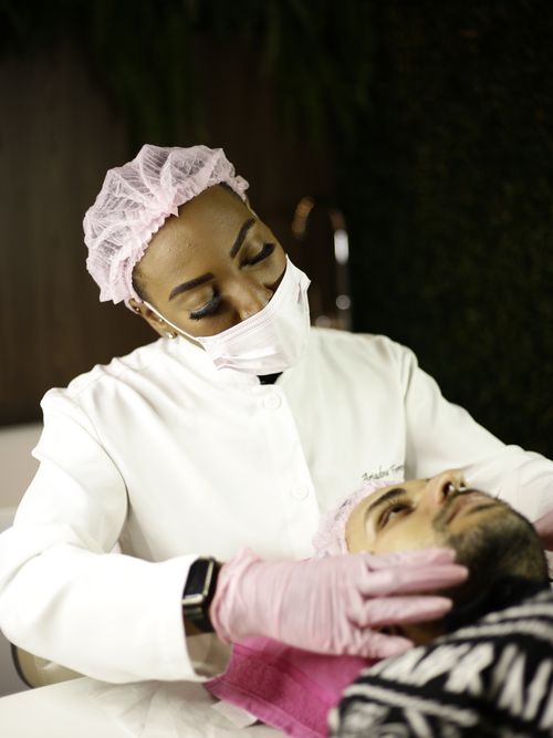 Free A skincare specialist wearing a mask applies treatment to a client at a spa. Stock Photo