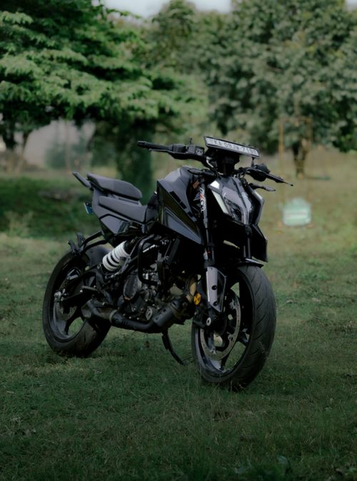 Free Sleek modern black motorcycle parked outdoors on a green grass field. Stock Photo