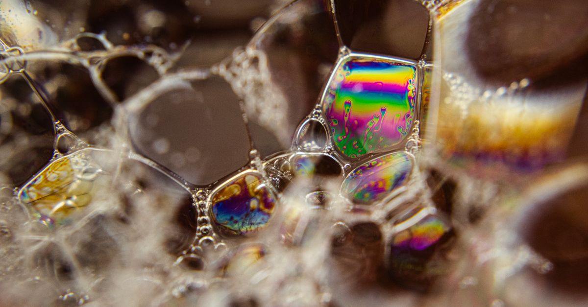 Imagem vibrante em close-up de bolhas de sabão coloridas criando um padrão e textura abstratos.