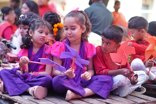 Free Joyful children with painted faces playing with pinwheels at a vibrant festival outdoors. Stock Photo