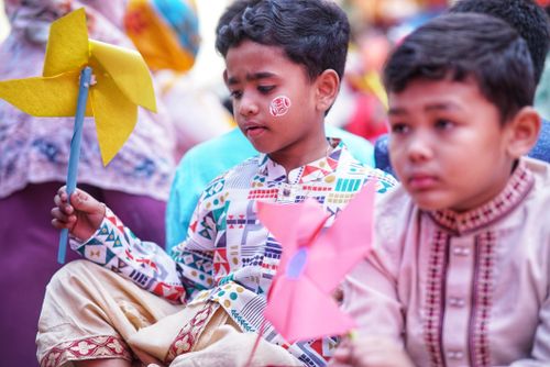 Free Two children holding colorful pinwheels outdoors, enjoying a festive event. Vibrant cultural attire adds to the joyful atmosphere. Stock Photo