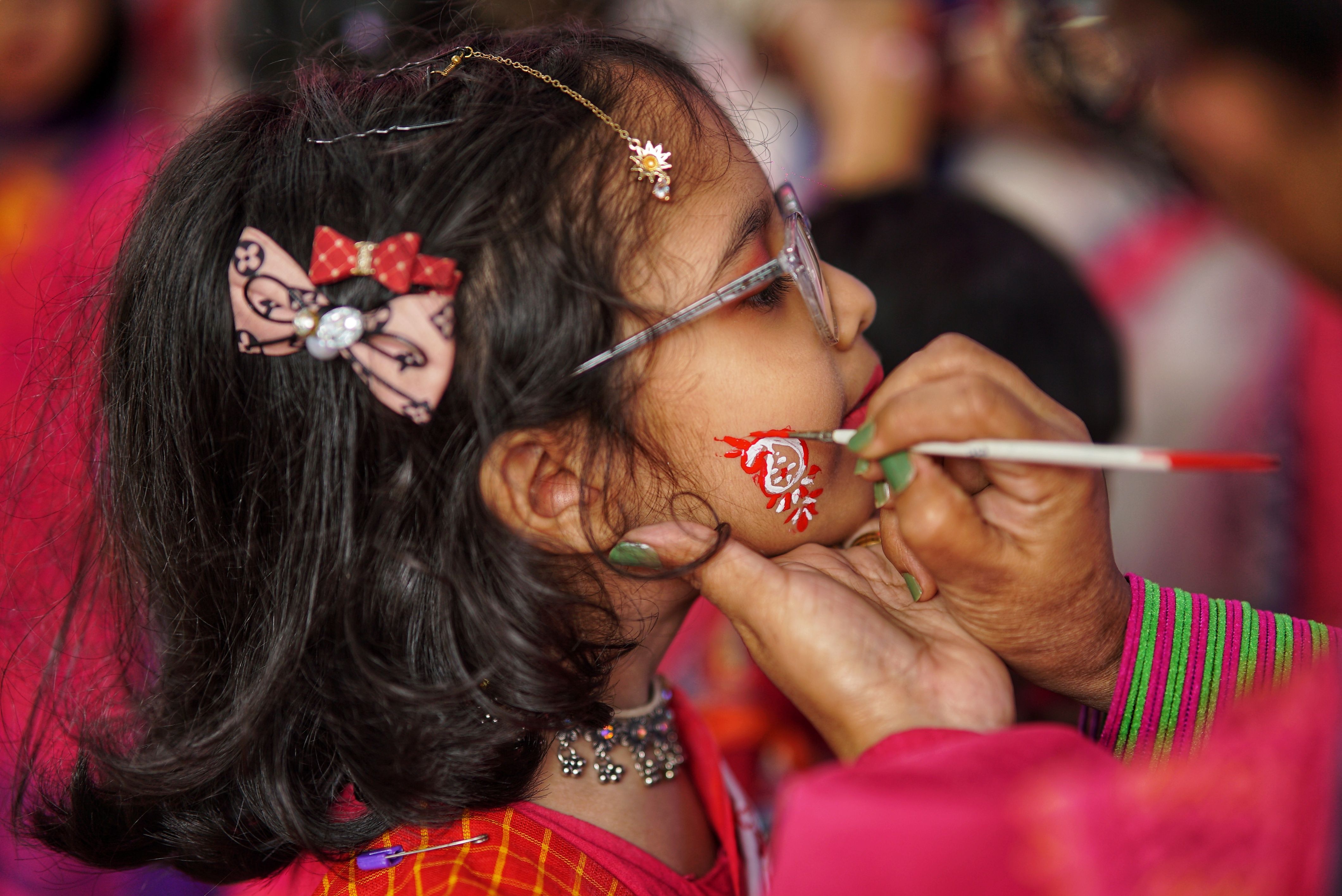 A young girl getting her face painted in vibrant colors during a festive event.
