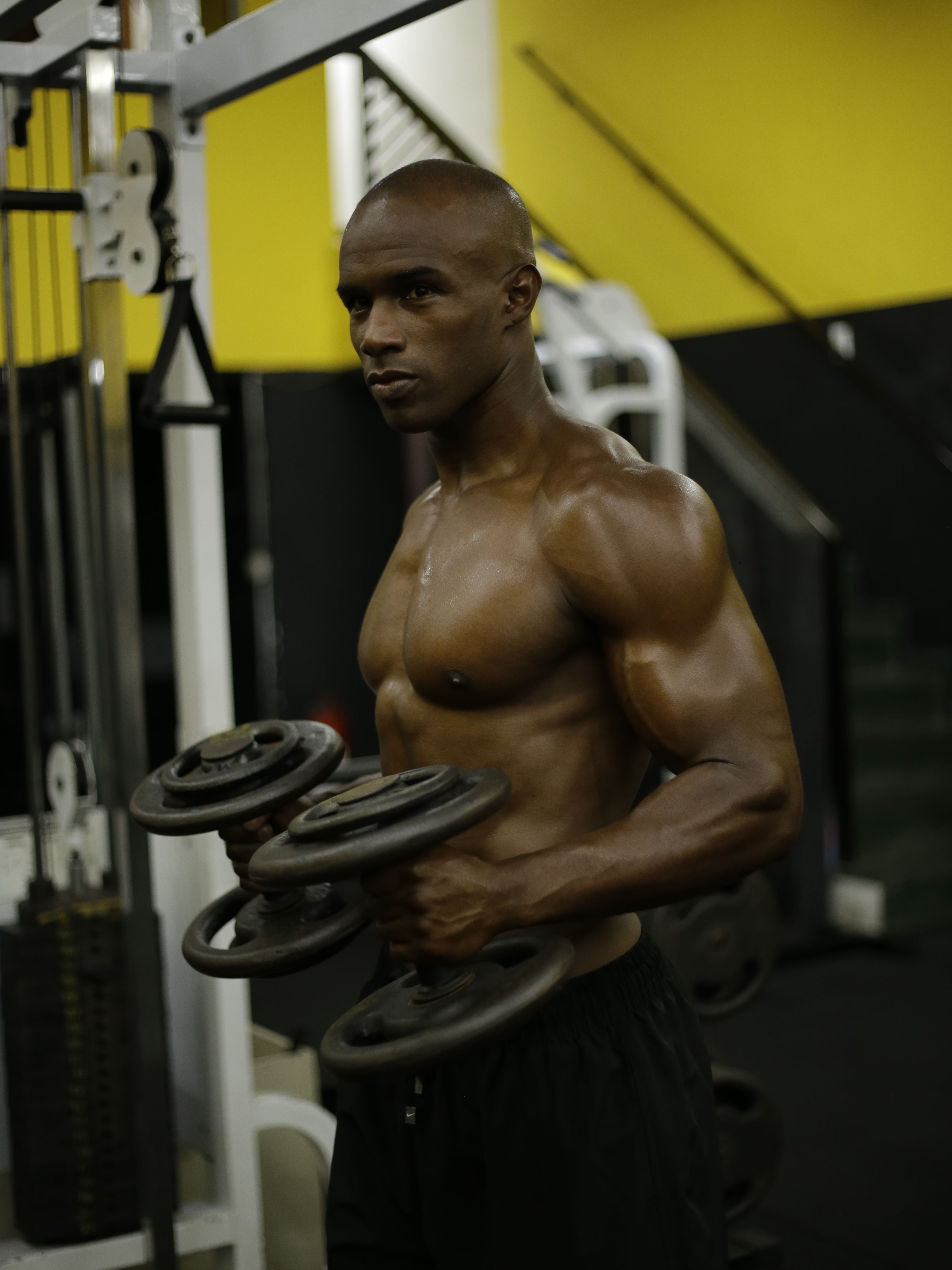 Fit man exercising with dumbbells in a gym setting. Focus on fitness and strength.
