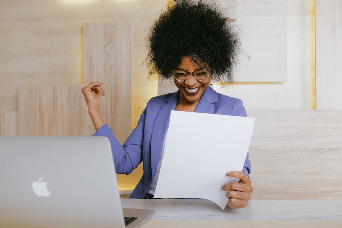 Cheerful woman celebrating success with document at work