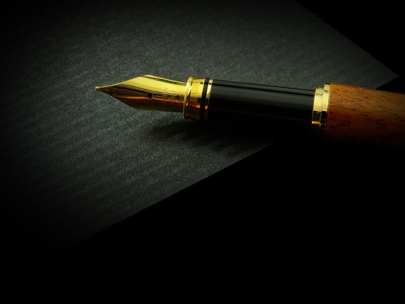A fountain pen resting on dark textured paper.