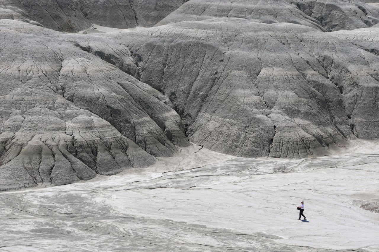 a lone hiker walks across a gray barren rocky landscape depicting isol