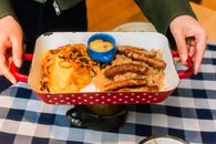 Delicious platter of German sausages with sauerkraut and mustard served on checkered cloth.