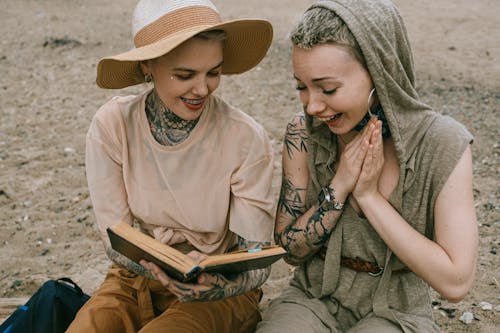 Foto De Mulheres Rindo Enquanto Lêem Um Livro