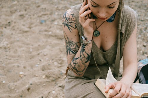 Wanita Memegang Buku Saat Menggunakan Smartphone