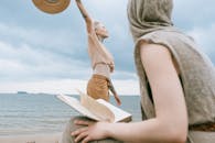 两个女人在海滩上享受休闲时光，一个读书，另一个拥抱自由