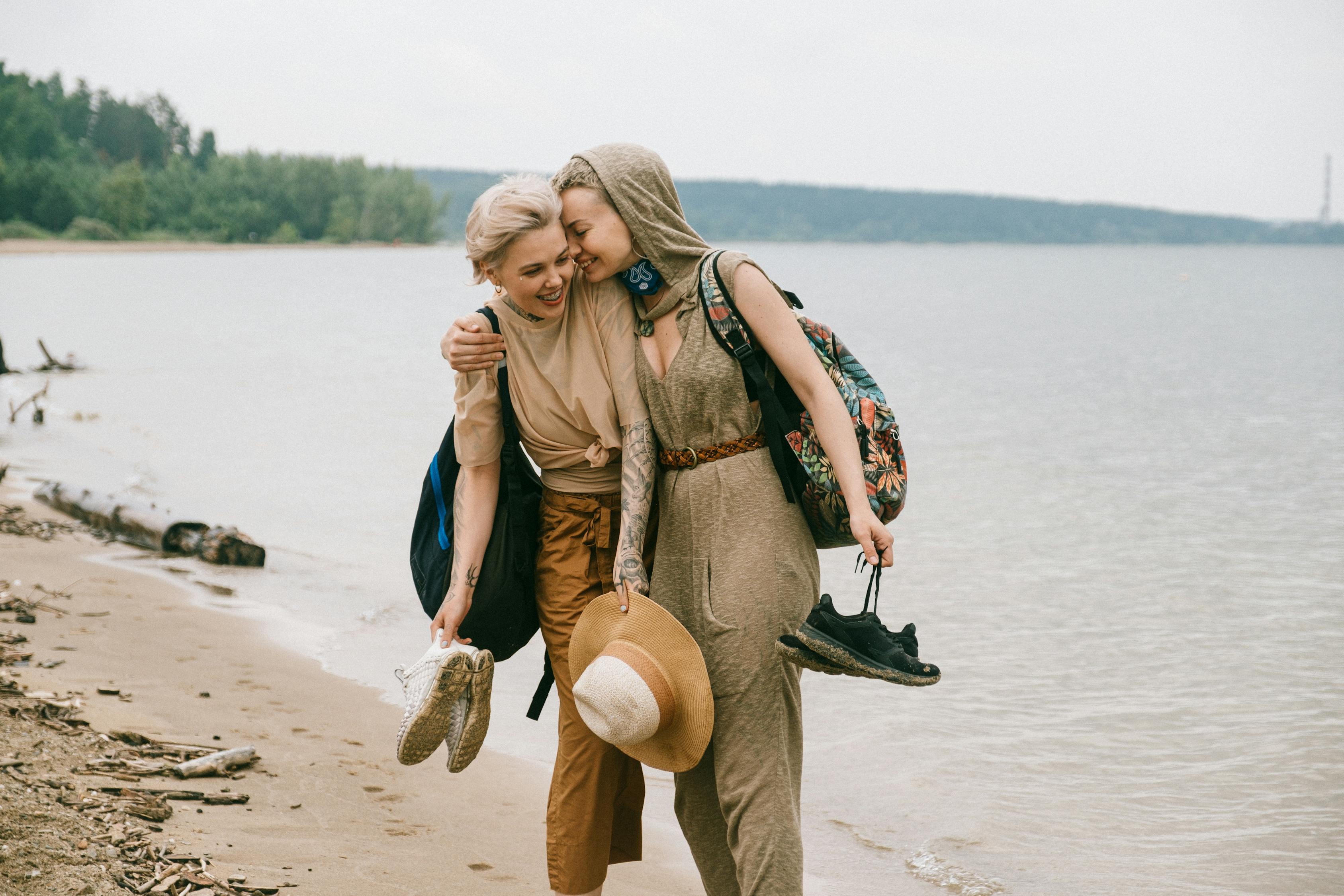 Photo of Women Embracing While Standing on Beach