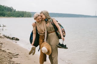 Photo of Women Embracing While Standing on Beach