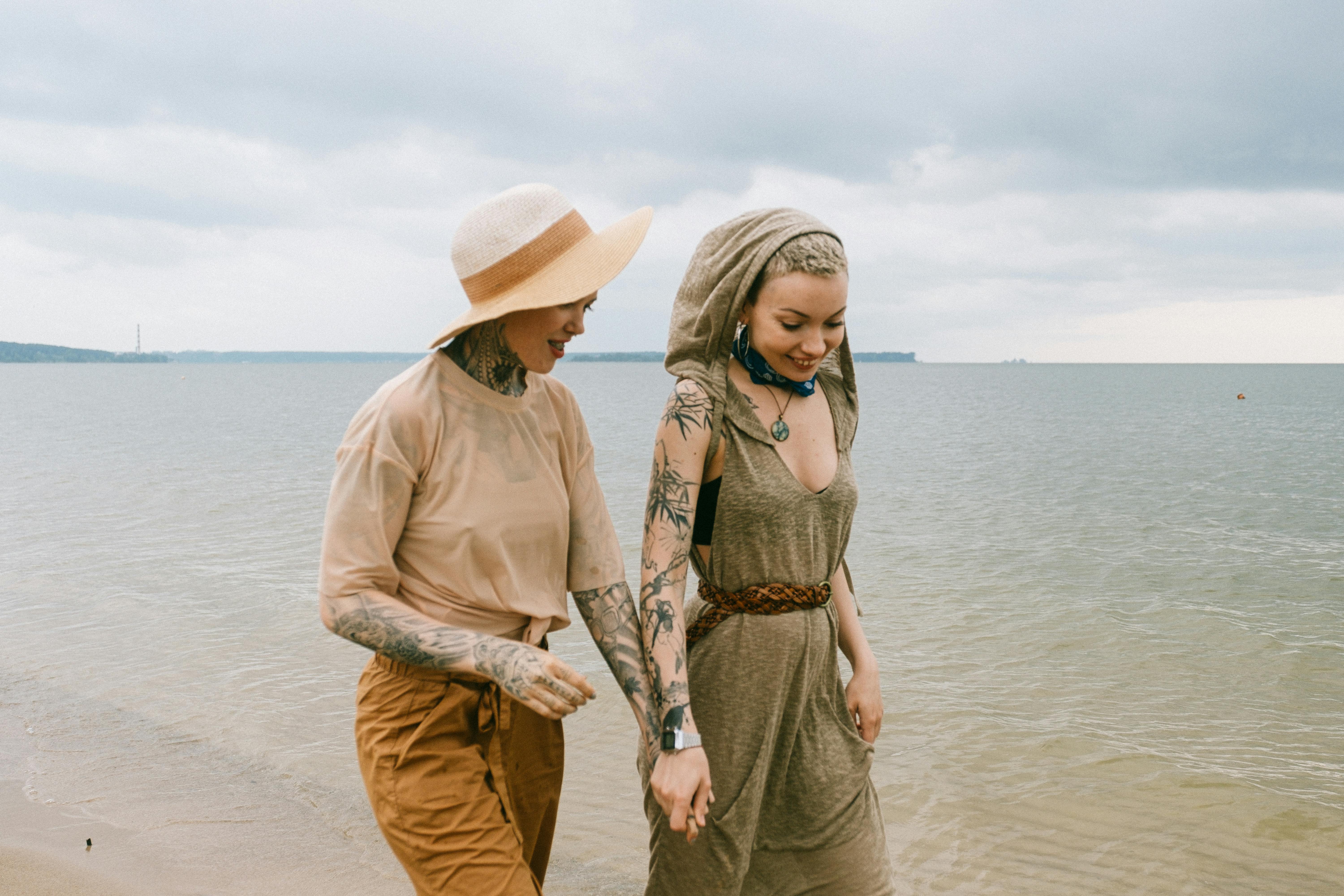 photo of women holding hands while walking on beach