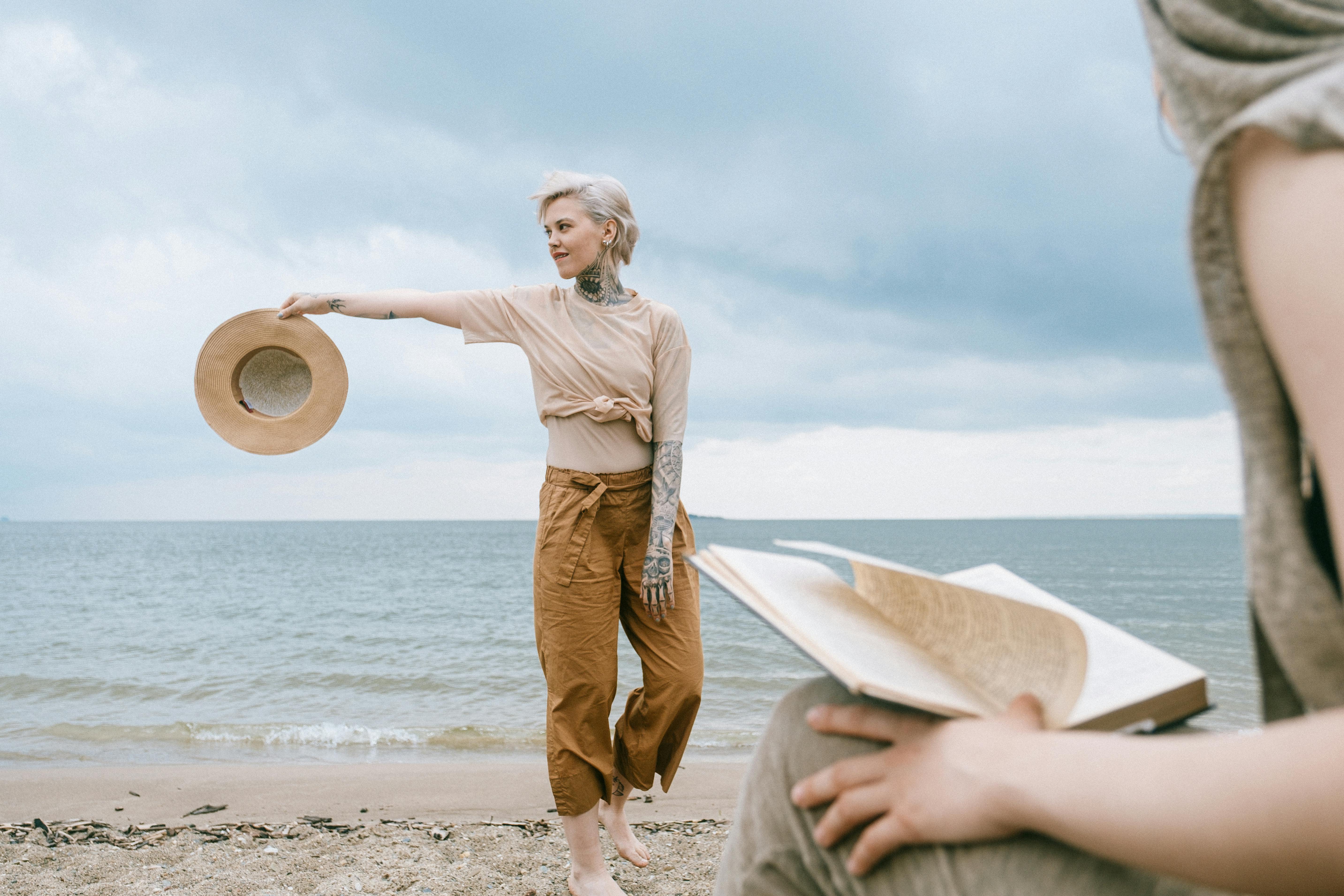 两个朋友在海滩上平静地度过了一天，一个戴着帽子，另一个在读书