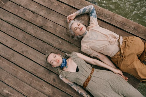 High Angle Photo of Women Lying Down on Wooden Planks