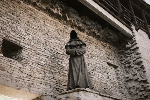 Cloaked statue within an ancient stone wall, exuding a mysterious and historical ambiance.