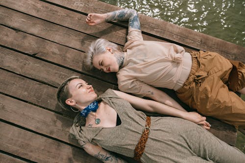 Free High Angle Photo of Women Lying Down on Wooden Planks Stock Photo