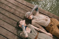 两名纹身女子在水边的木甲板上放松身心，展现了她们的友谊