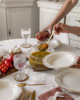 A cozy scene of homemade vegan soup being served, featuring fresh vegetables on a white table setting.