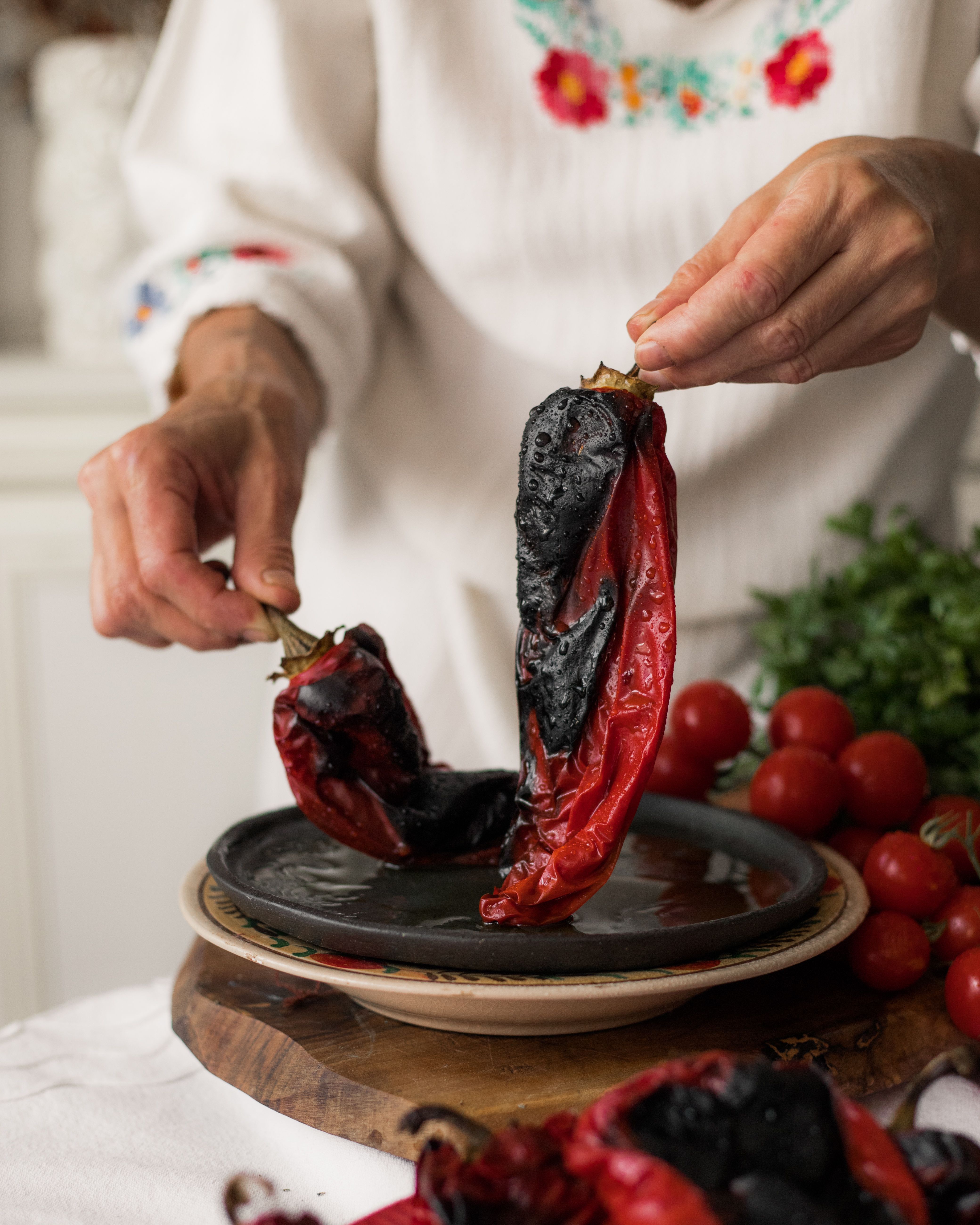 Hands peeling roasted red peppers