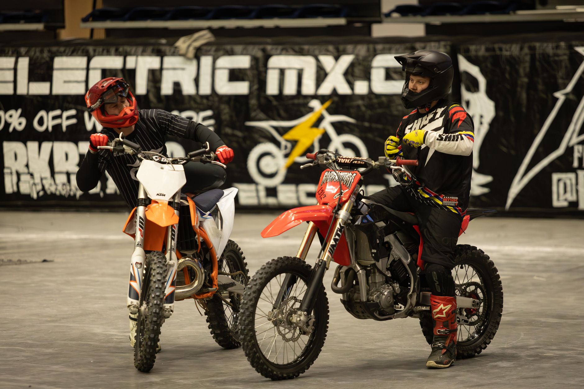 Two motocross riders readying for an indoor race event in full gear.