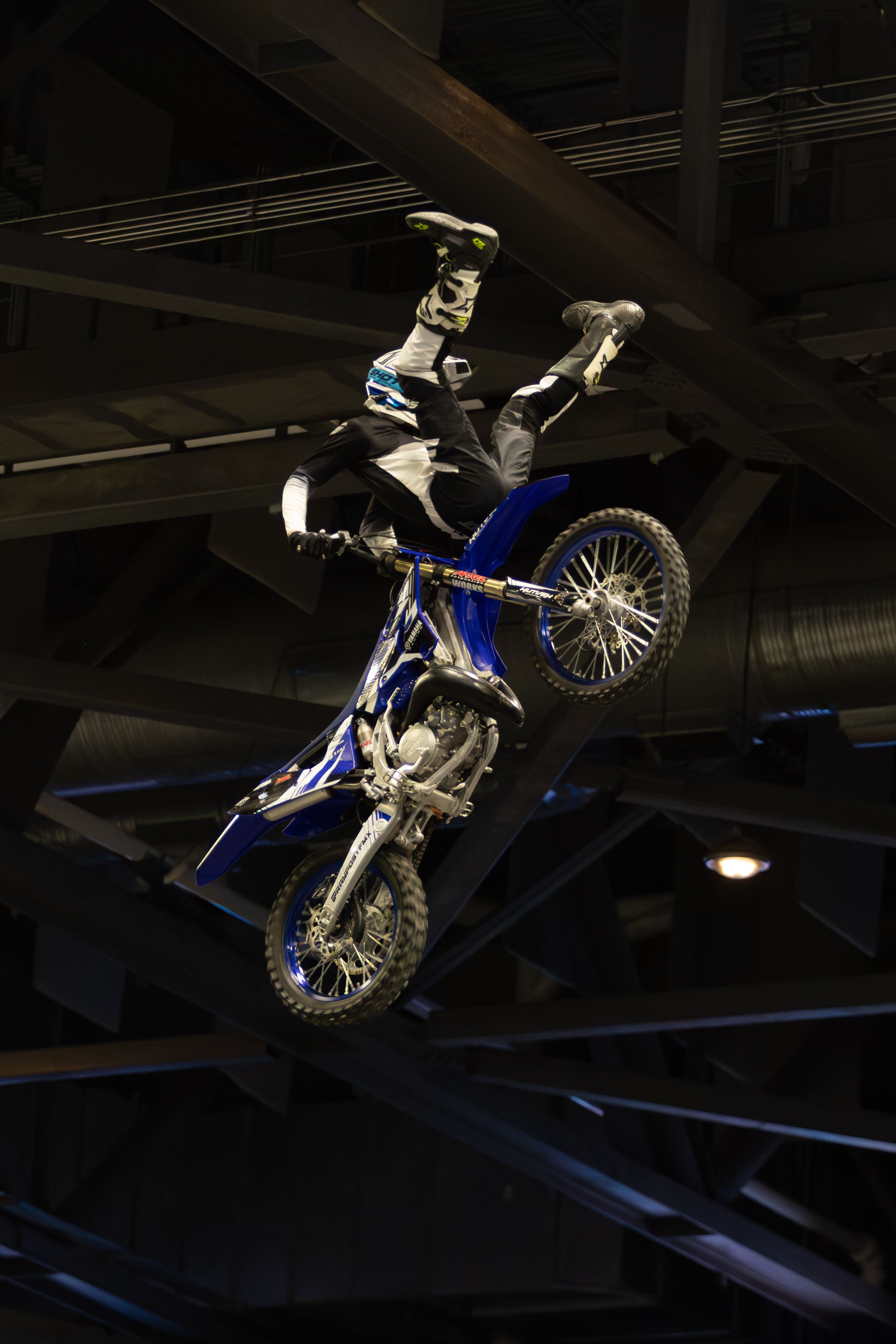 Motorcyclist performing a thrilling stunt on a dirt bike indoors.