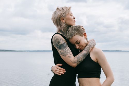 Free A tattooed couple shares an affectionate embrace by the seaside, showcasing love and trust. Stock Photo