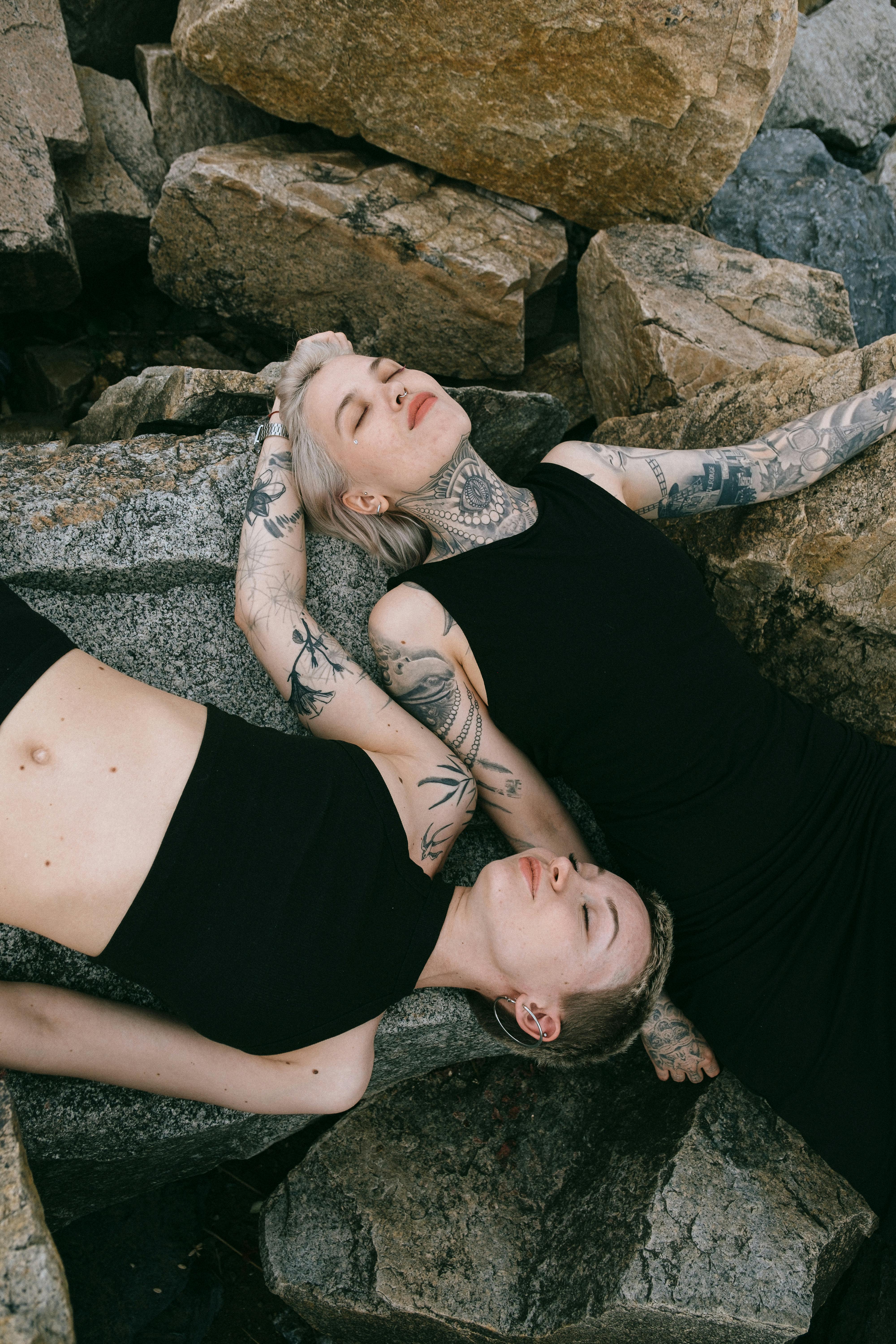 women in black clothing lying on gray rocks