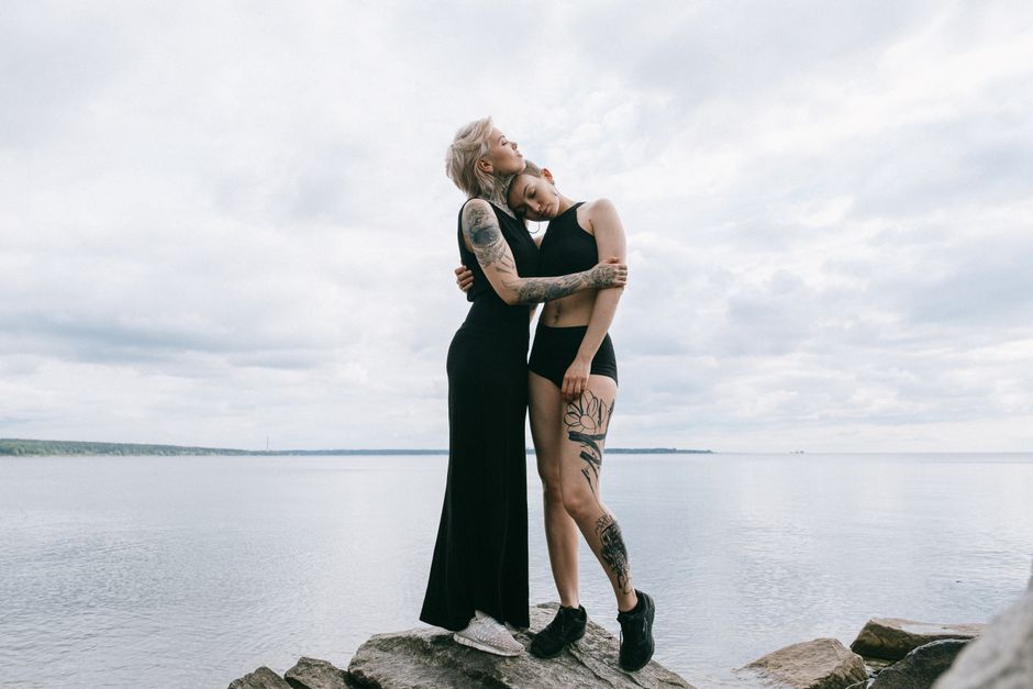 A romantic couple embraces on the rocky shoreline under a cloudy sky, symbolizing love and connection.