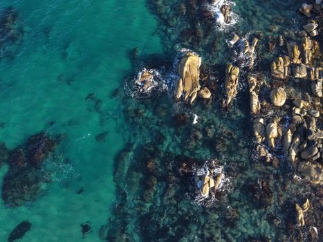 A stunning aerial shot of a rocky coastline with vibrant turquoise waters, showcasing natural beauty and tranquility.