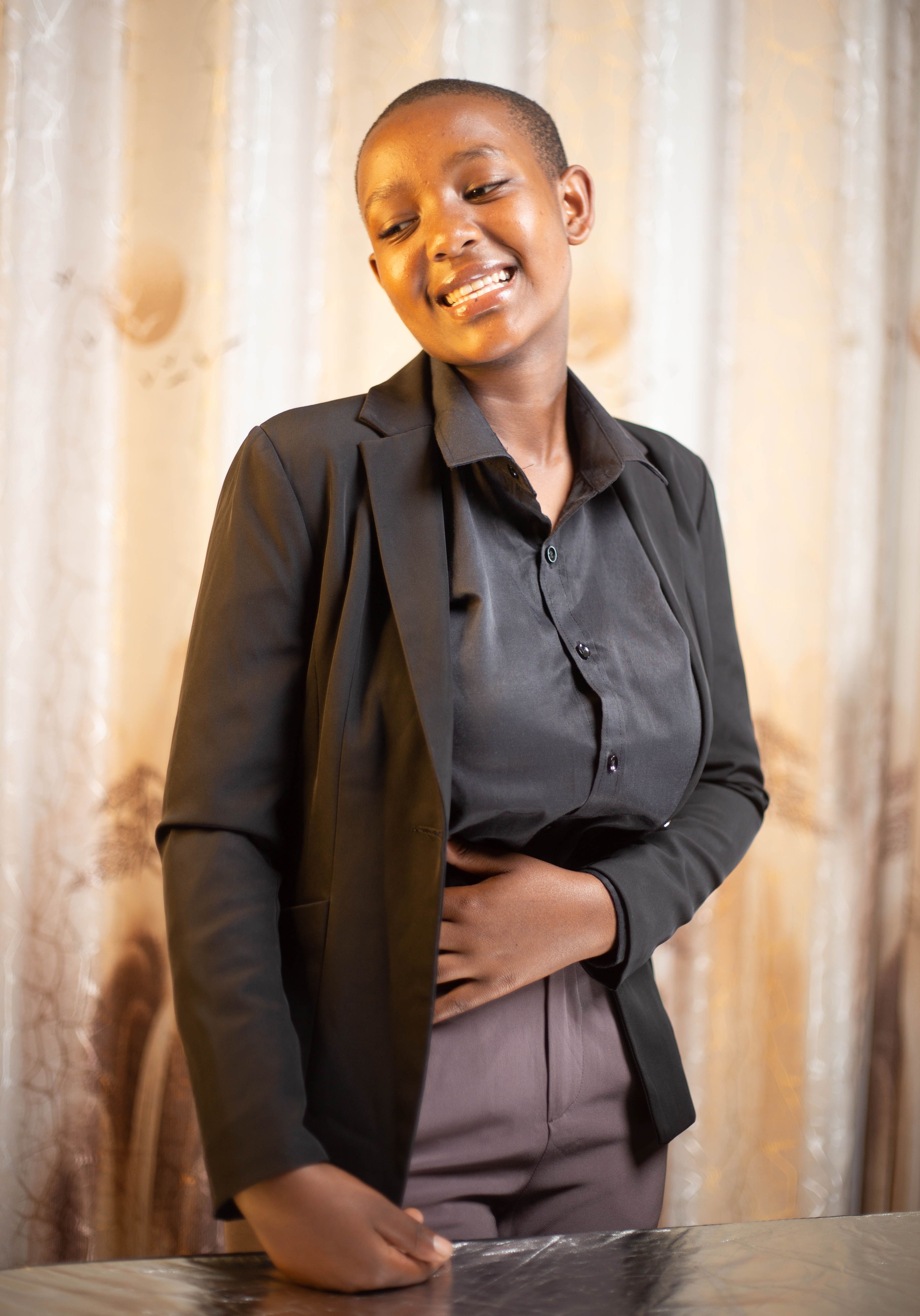 Confident woman smiling in formal attire indoors, conveying professionalism and positivity.