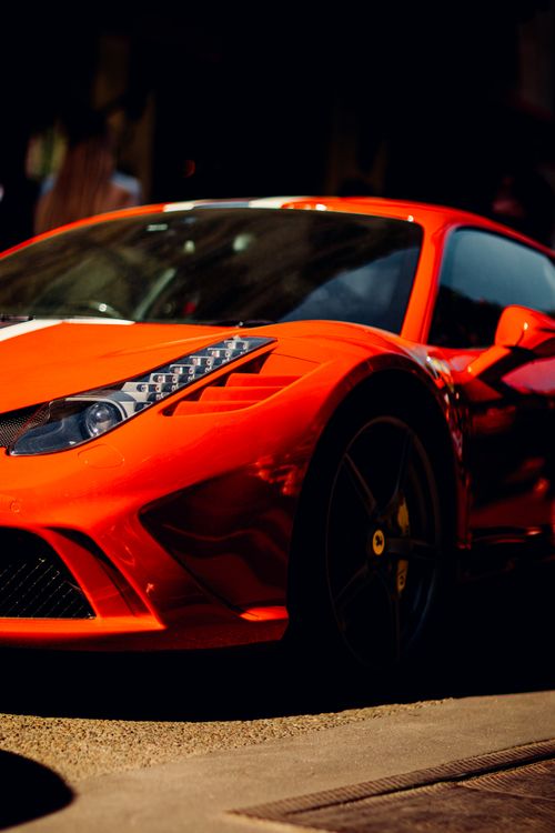 Free Close-up of a sleek red sports car parked outdoors under bright sunlight. Stock Photo